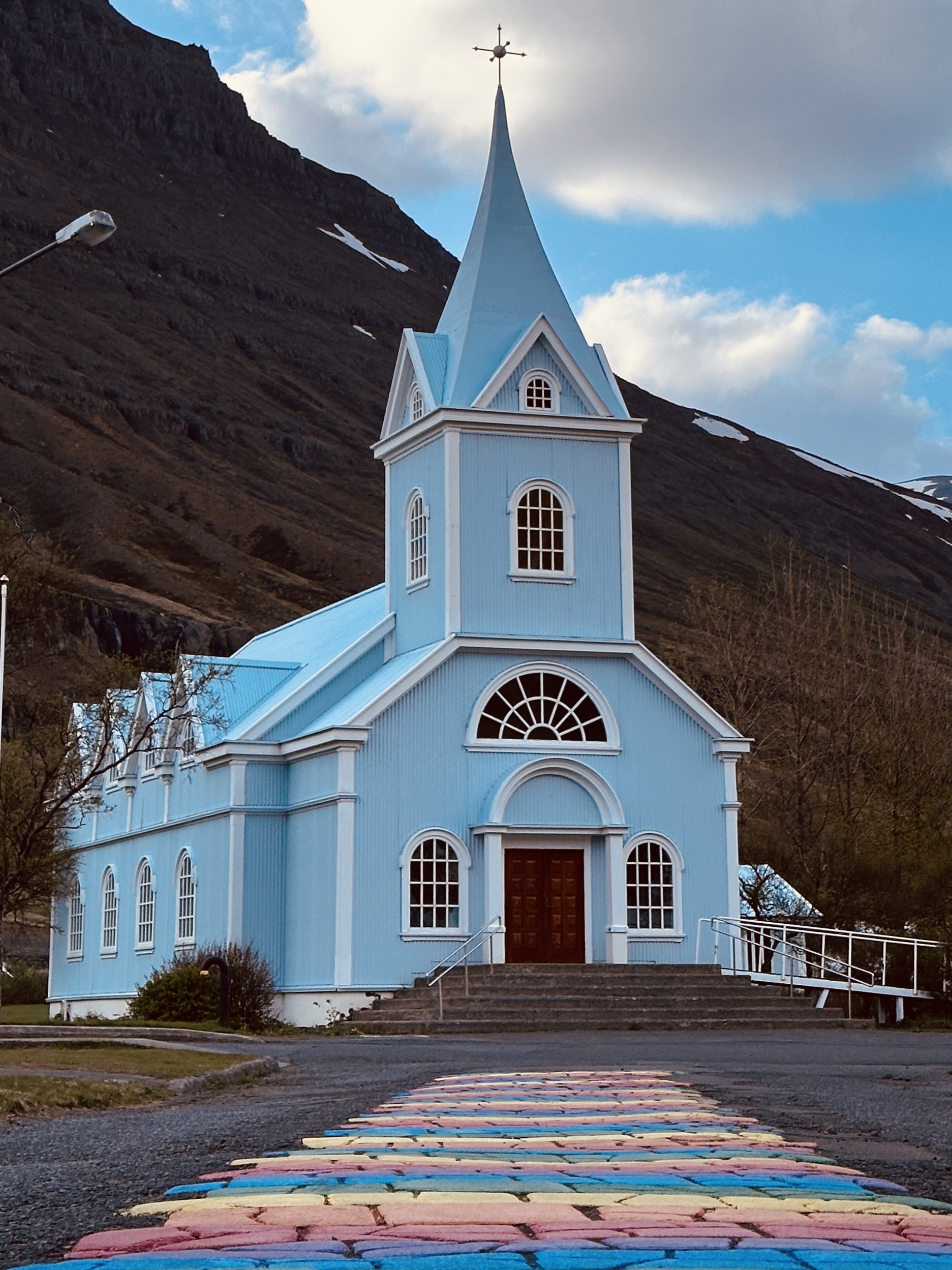 Kerkje en regenboogpad in Seydisfjordur, IJsland.
